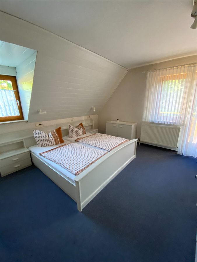 Doppelzimmer unter der Dachschräge mit weißem Holzbett